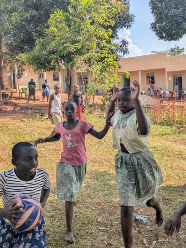 Pupils playing with a basketball on the grass outside the school